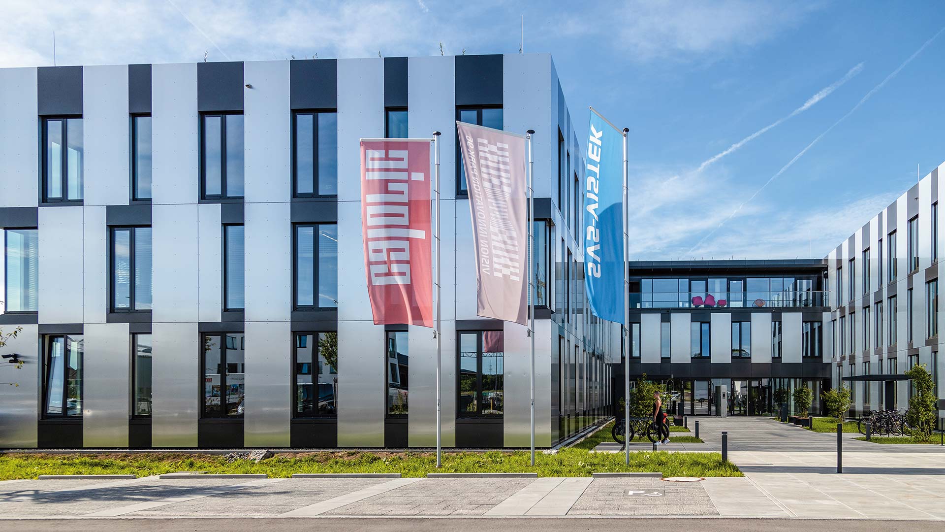 Drei Fahnenmasten vor einem modernen Gebäude