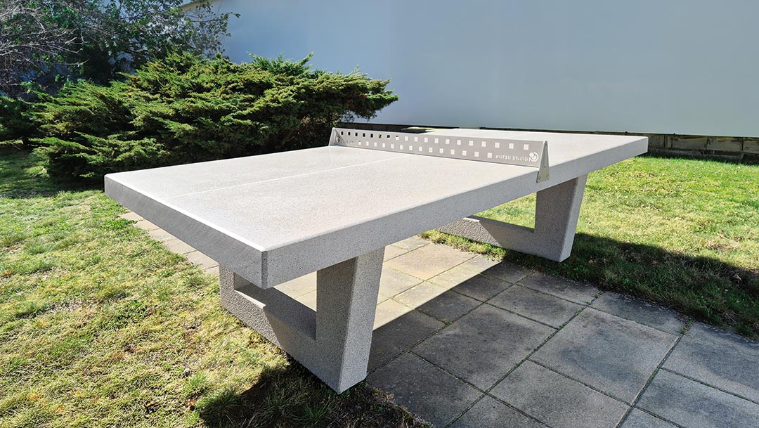Outdoor Tischtennisplatte aus Beton mit Schlägern und Ball auf Pflastersteinen
