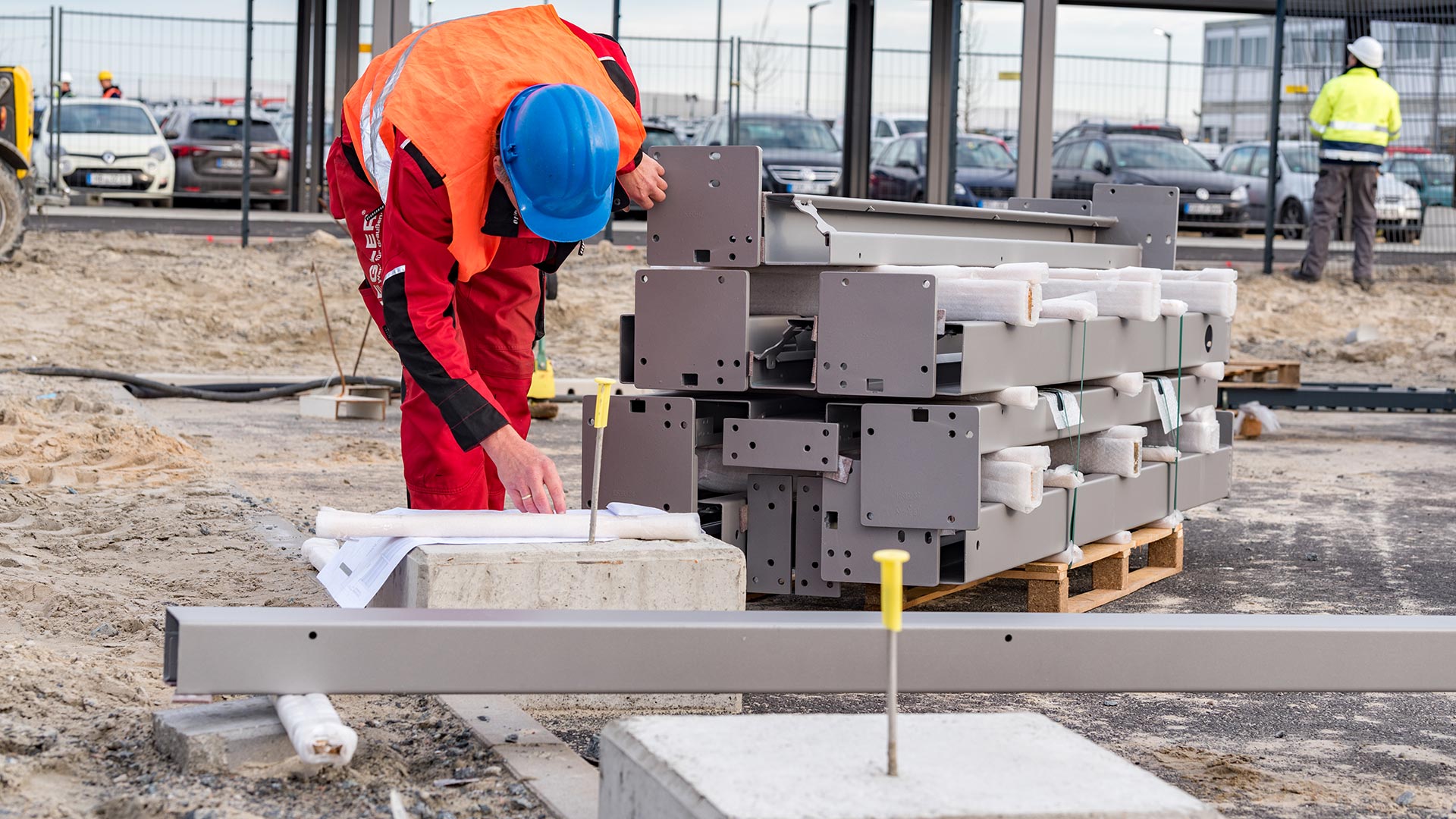 Mitarbeiter von ZIEGLER prüft Baupläne neben gestapelten Stahlträgern