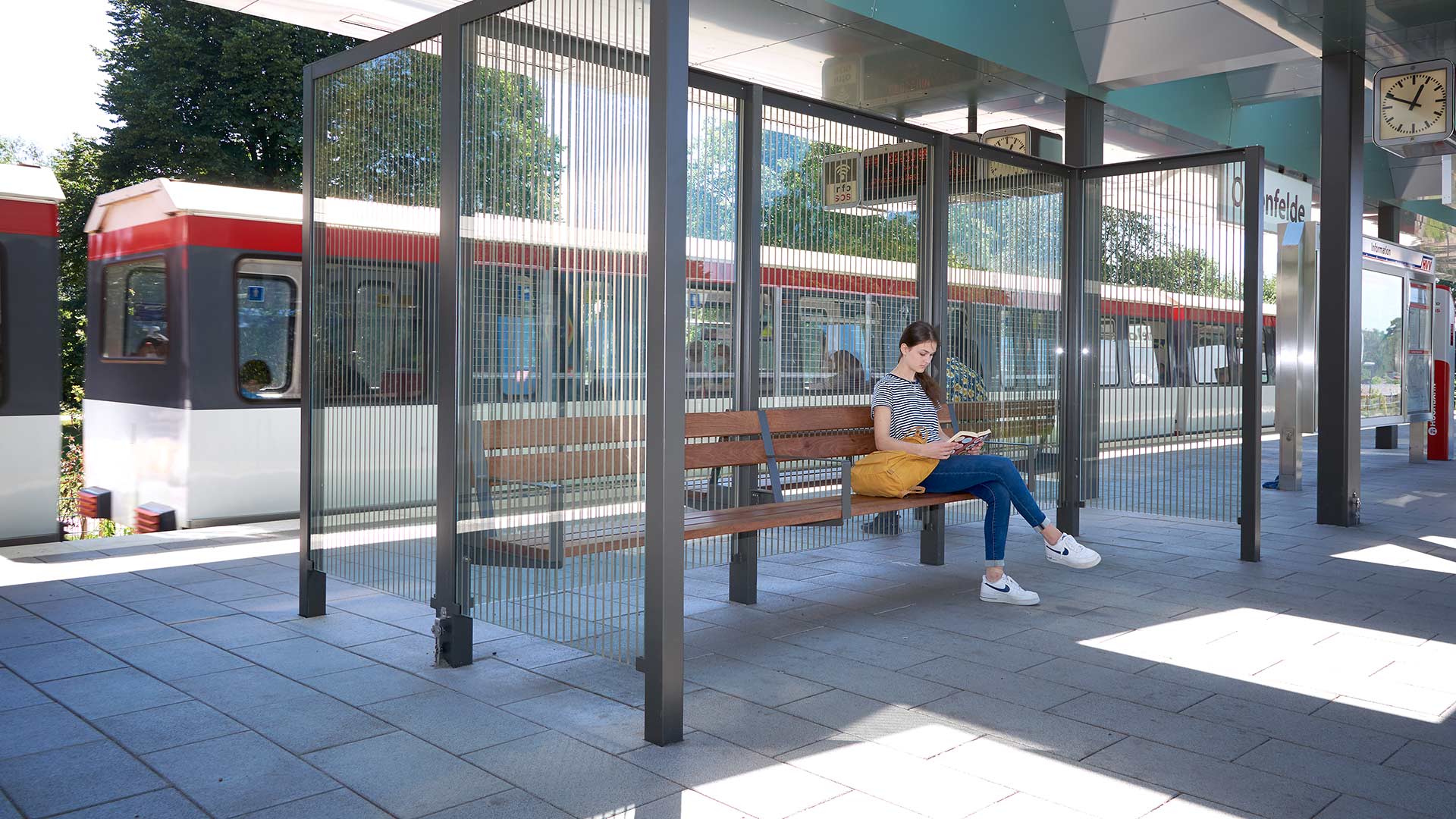 Frau wartet am Bahnsteig in einer Überdachung