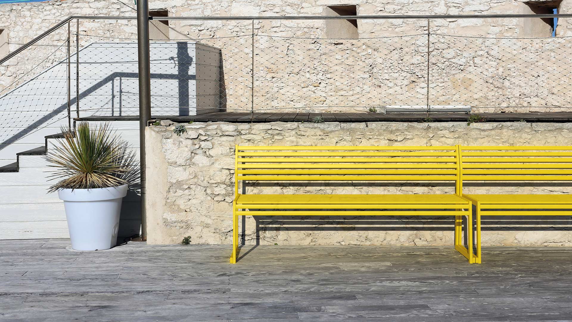 Gelbe Sitzbank vor einer Steinmauer