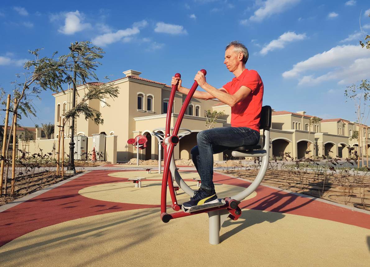Mann auf einem Outdoor Fitness Gerät vor einer mediterranen Stadt
