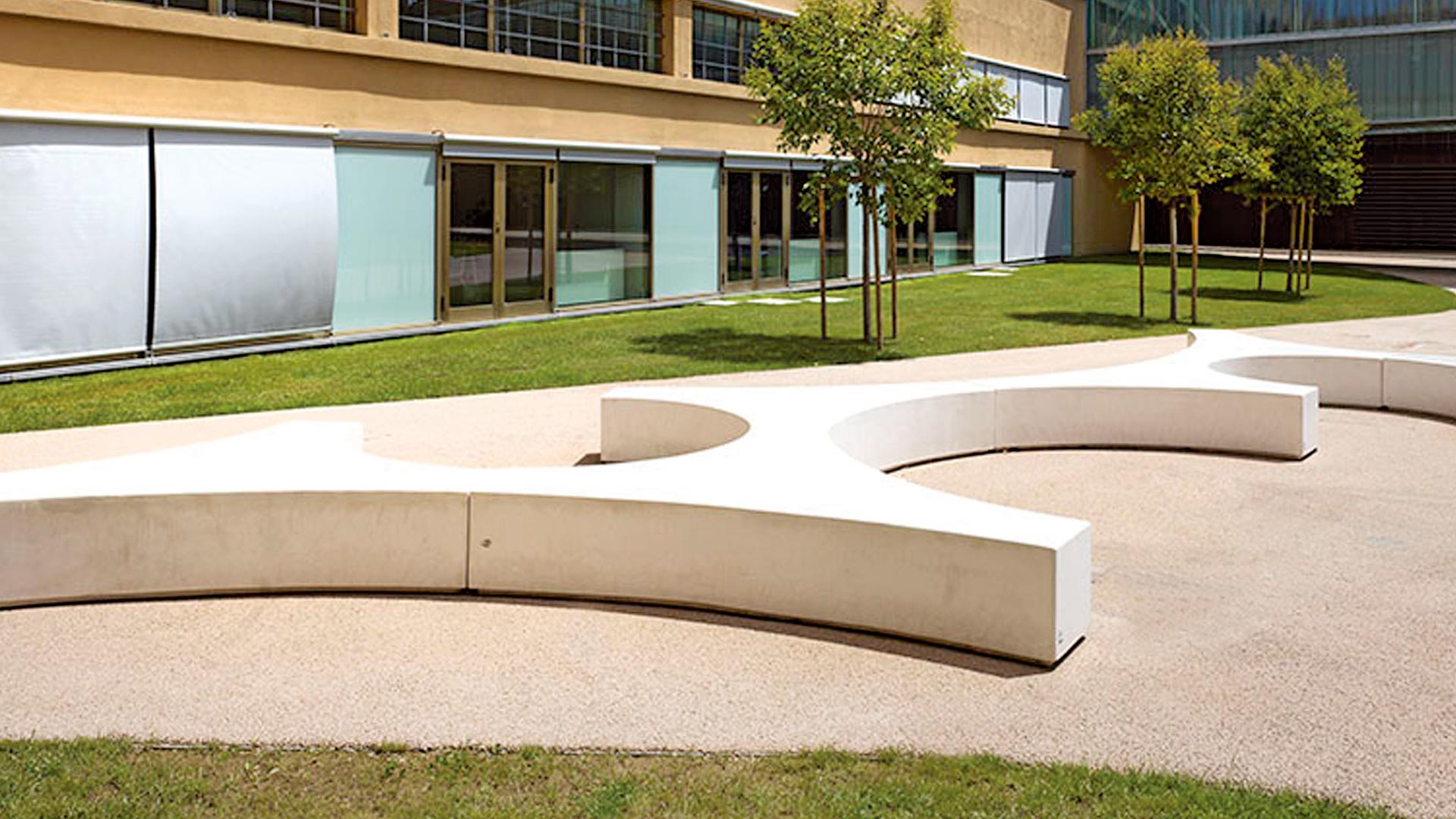 Moderne weiße Betonsitzinsel auf einem Hof mit einer Gebäudefassade im Hintergrund