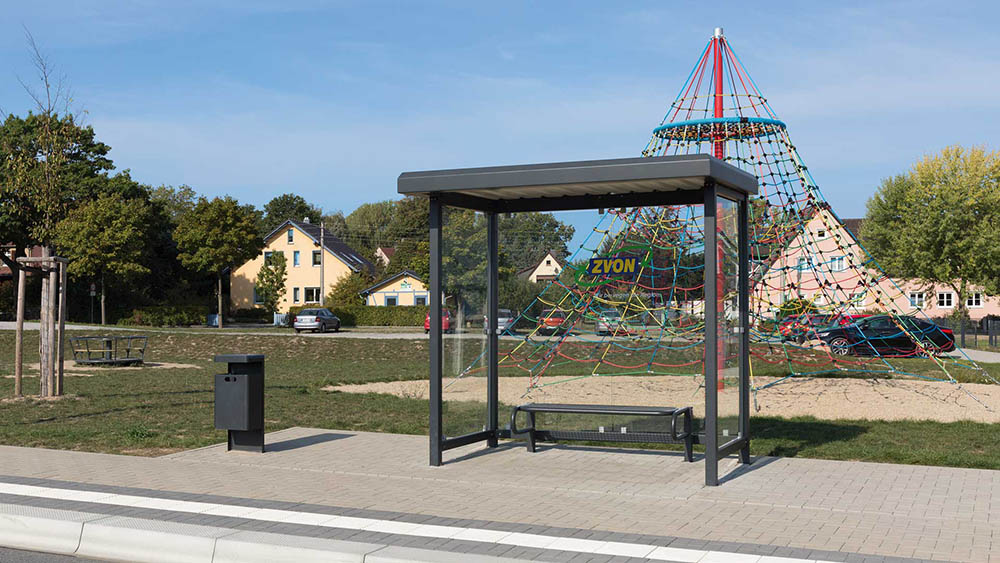 Bushaltestelle STADT mit Anfallbehälter vor einem Spielplatz
