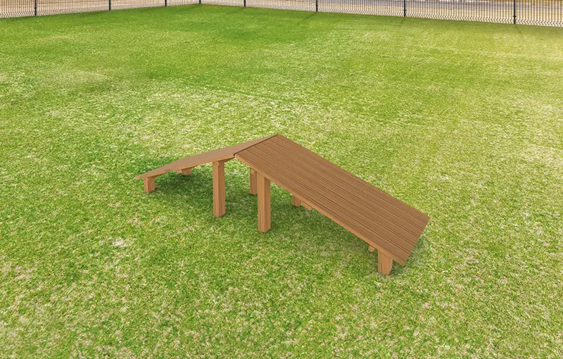 Holzrampe mit zwei Abschnitten auf einer Rasenfläche, umgeben von einem Zaun.