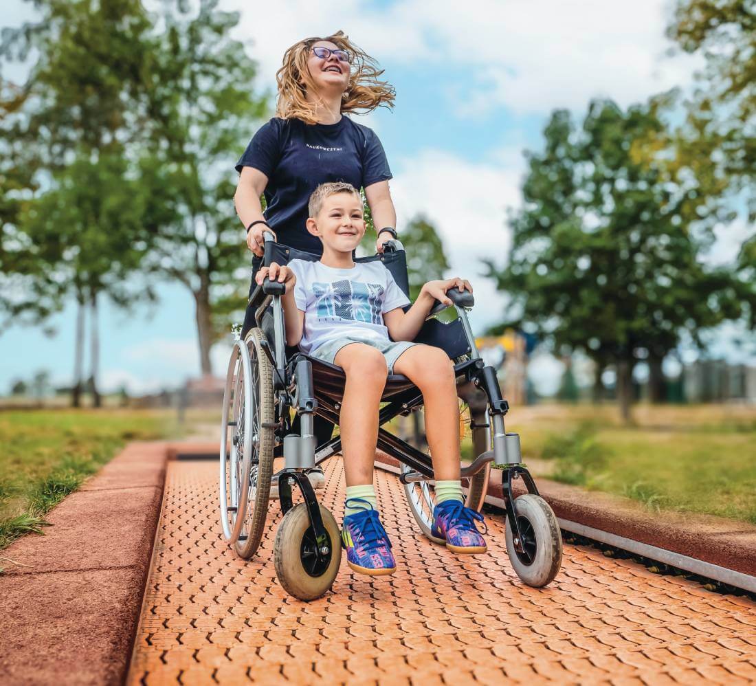 Kind im Rollstuhl auf einem barrierefreien Bodentrampolin