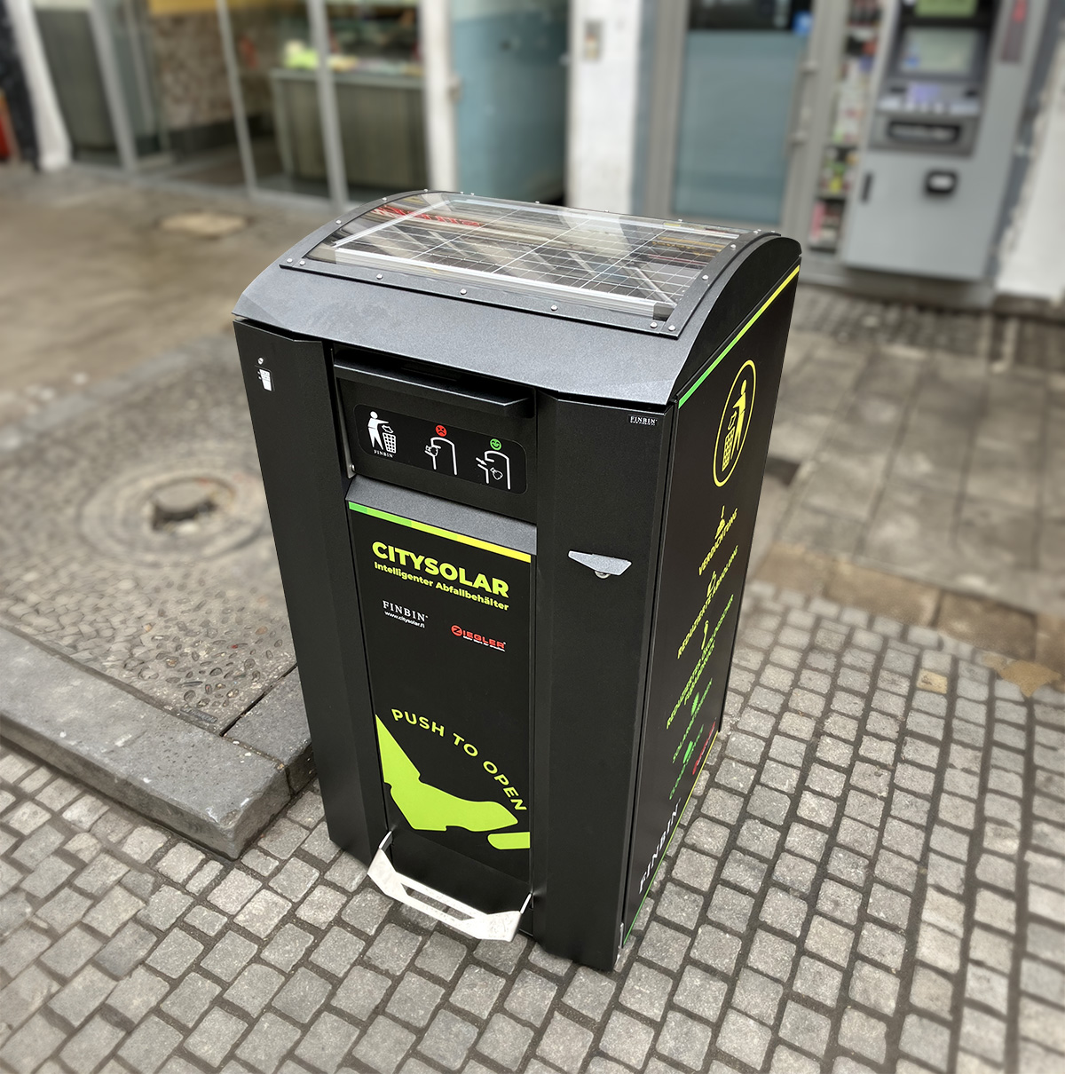 Abfallbehaelter CITYSOLAR 2.0 am Straßenrand mit sichtbarem Solarpanel