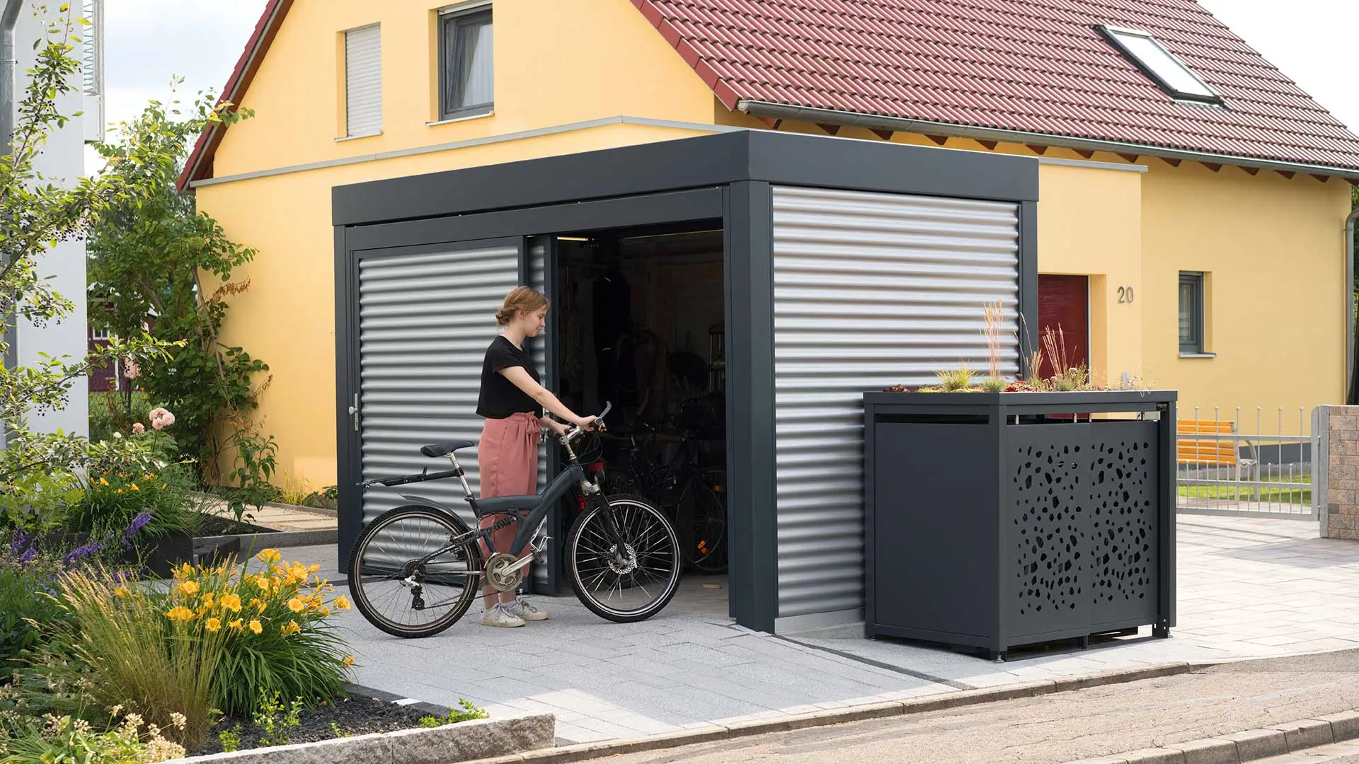 Fahrradhaus MULTIPORT® und Müllbehälterschrank STYLEOUT TOMO vor einem Haus