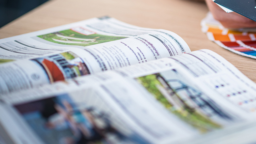 Aufgeschlagener Katalog mit Text und Bildern auf einem Tisch