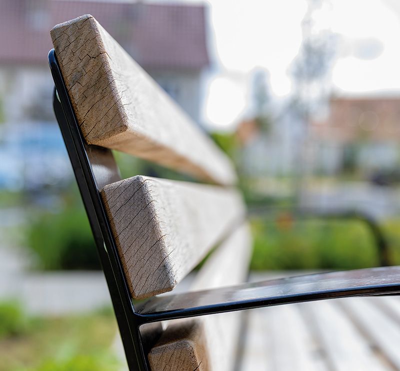 Nahaufnahme der Rückenlehne einer Holzbank mit Metallgestell im Freien