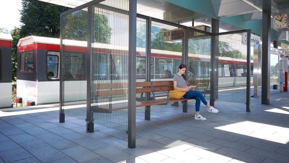 Frau wartet am Bahnsteig in einer Überdachung