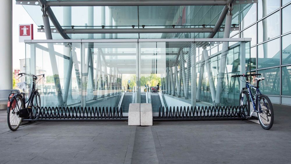 Fahrradständer mit zwei Fahrrädern vor einem modernen Gebäude mit Glasfassade