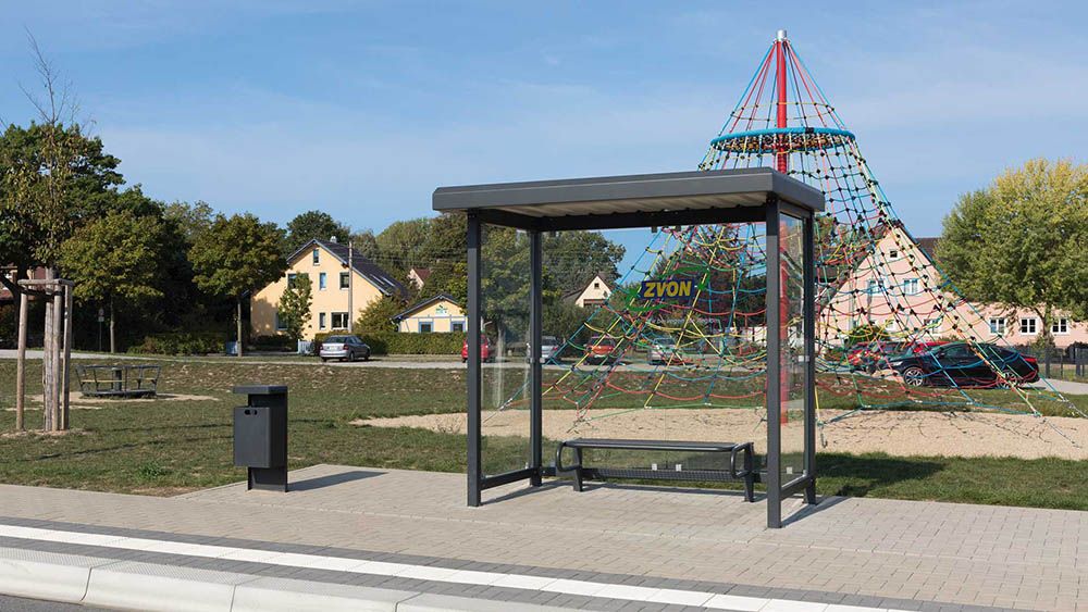 Bushaltestelle STADT mit Anfallbehälter vor einem Spielplatz