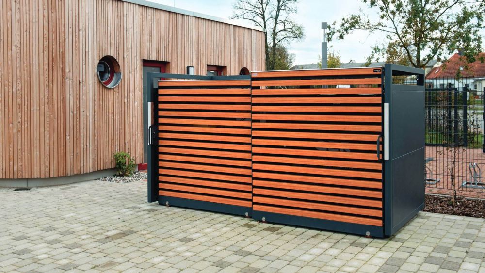 Mülltonnenbox in Holzoptik auf einem gepflasterten Platz