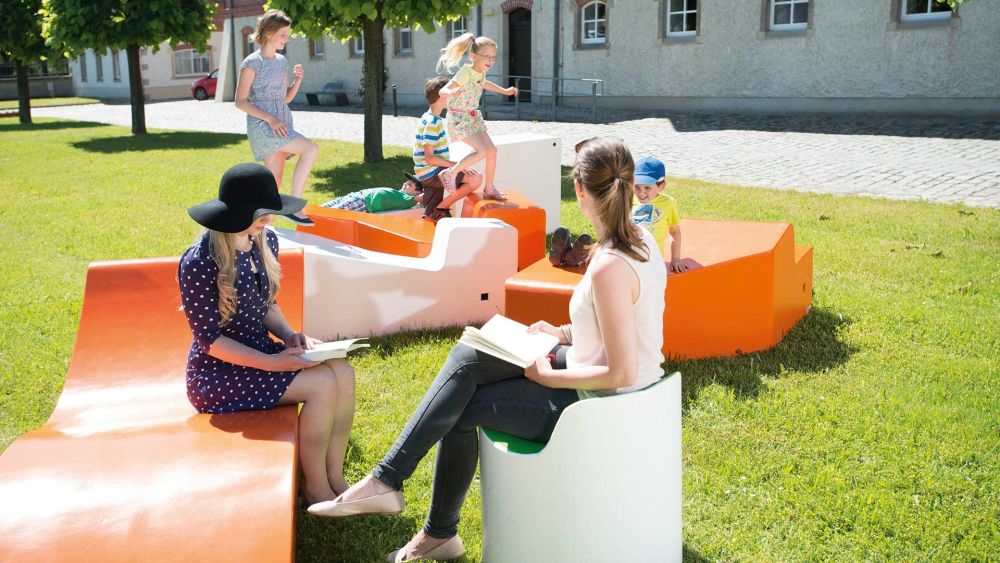 Sitzmöbeln im Park geschwungenen orange und weißen auf denen Frauen sitzen und lesen